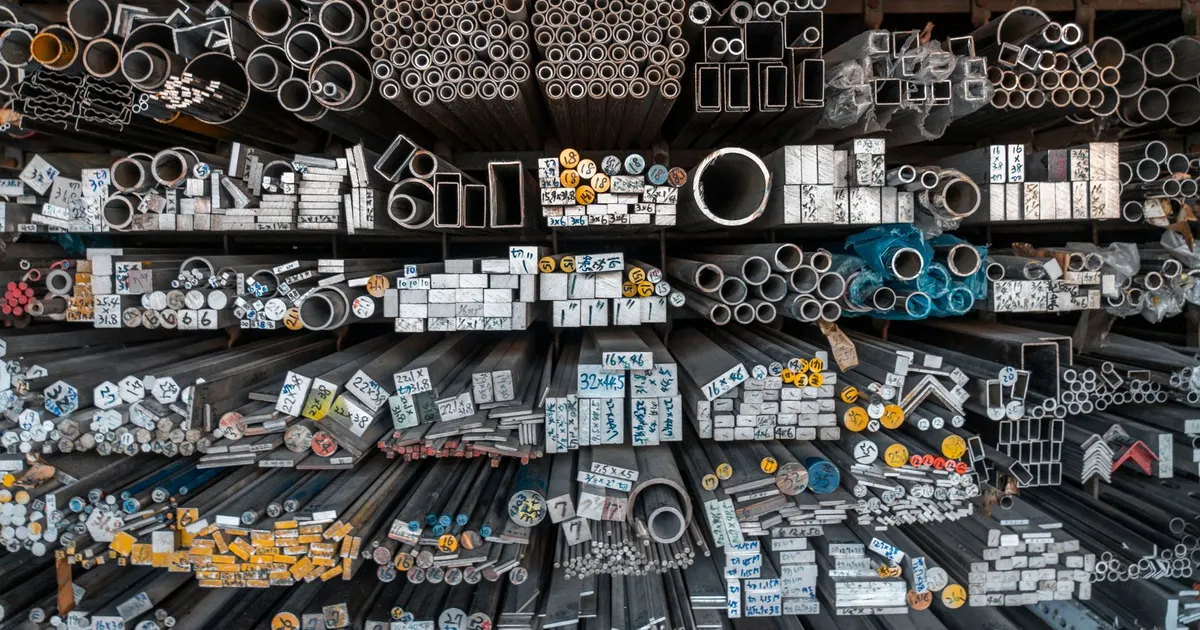 Racks of steel tubes, bars and hollow sections stored in an industrial warehouse, the stock used to build a steel tube machine frame